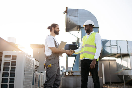 Two HVAC contractors shaking hands on a rooftop next to commercial HVAC equipment