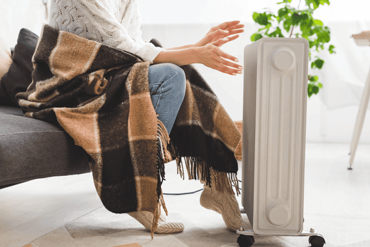 a woman in a shawl using a space heater instead of a mini split in her home